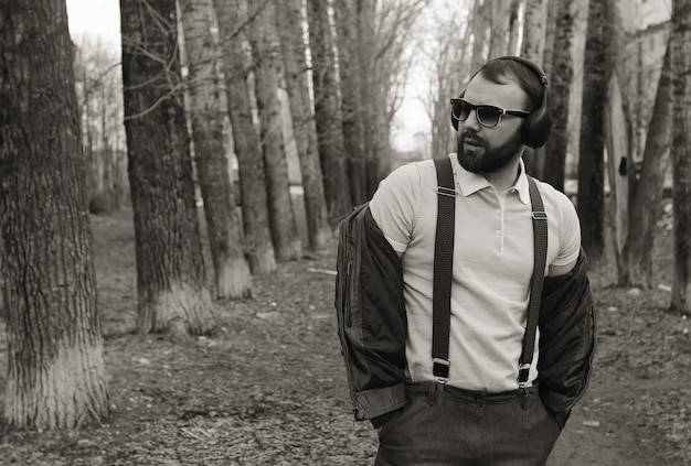 Homem de barba monocromática ouve música no parque