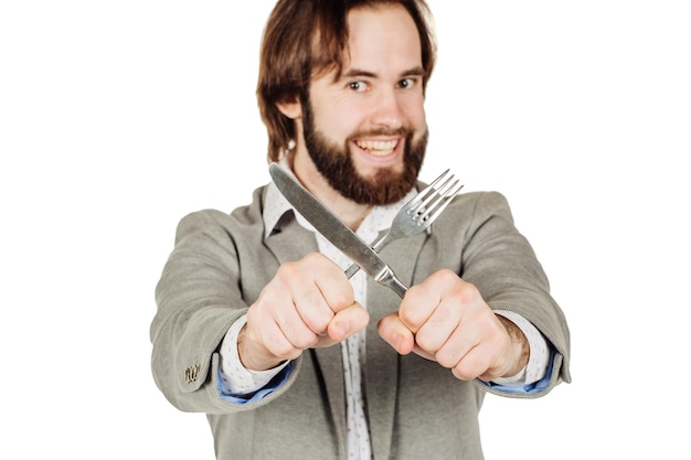 Homem de barba segurando talheres garfo e faca no conceito de estilo saudável de dieta alimentar isolado em um fundo de estúdio branco