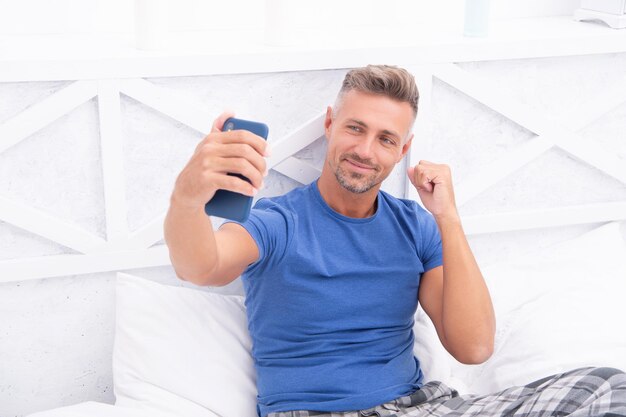 Foto homem de blog sorridente com telefone no quarto homem de blog com telefone vestindo camisa