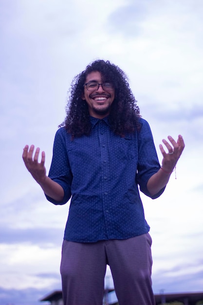 Homem de cabelo cacheado com óculos ri