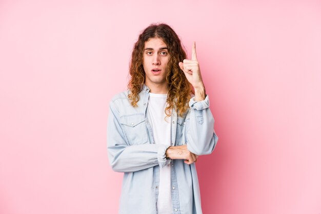 Homem de cabelo comprido posando isolado, tendo uma ótima ideia, o conceito de criatividade.