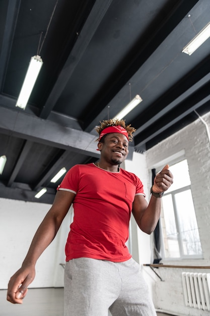 Homem de cabelo curto radiante repetindo sua atuação antes do evento principal enquanto usava roupas confortáveis