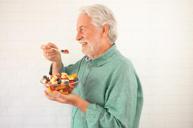 Homem de cabelos brancos sorridente pronto para comer uma salada de frutas frescas de verão Café da manhã ou hora do almoço alimentação saudável