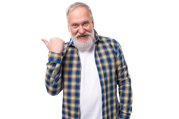 Foto homem de cabelos grisalhos aposentado sênior com barba em uma camisa mostra seu dedo indicador para o lado em um