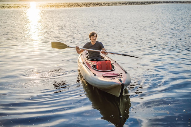 Homem de caiaque de viagem de verão remando caiaque de canoa transparente desfrutando de atividade esportiva recreativa