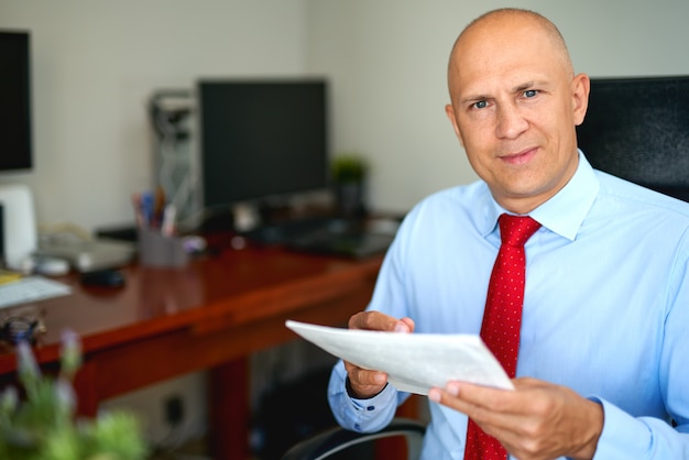 Homem de camisa azul e gravata vermelha no escritório