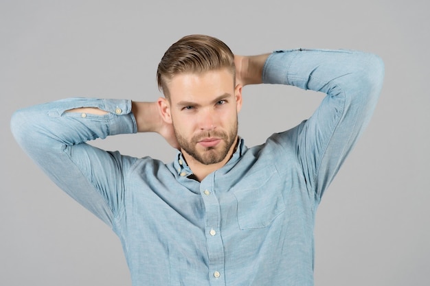 Homem de camisa azul elegante. Homem com rosto barbudo e corte de cabelo elegante. Modelo de moda em camisa casual. Estilo de moda e tendência. Cuidados com a pele e cabelo no salão de beleza.