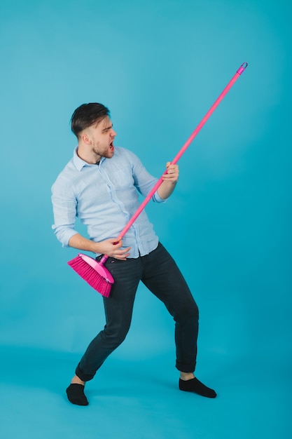 homem de camisa azul fica em fundo azul com vassoura rosa