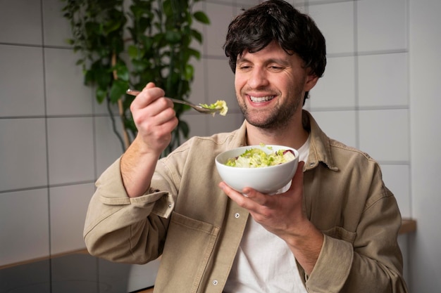 Foto homem de camisa bege comendo uma salada de vegetais para o almoço o conceito de alimentação saudável e estilo de vida