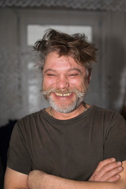 Foto homem de camisa de braços cruzados sorrindo com barba e bigode