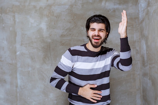 Homem de camisa listrada levantando a mão para chamar a atenção