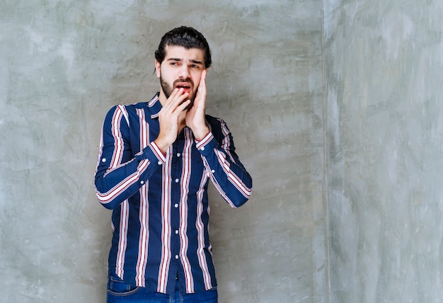 Homem de camisa listrada parece assustado e emocionado.