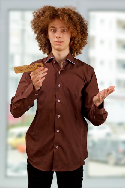 Foto homem de camisa marrom usa um pente de madeira