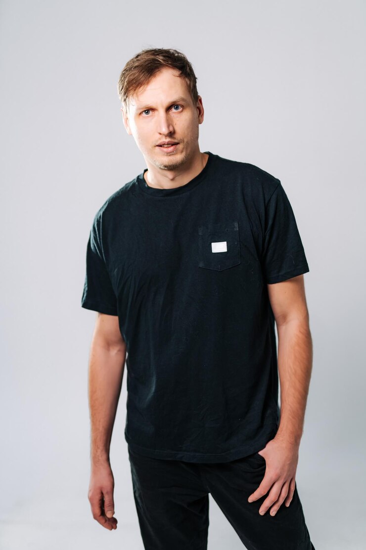 Foto homem de camisa preta posa em fundo cinza um homem de camisa negra está confiantemente olhando para a câmera com uma expressão neutra em um estúdio
