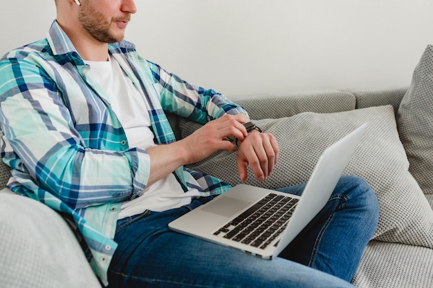 Homem de camisa sentado relaxado no sofá em casa na mesa trabalhando online no laptop