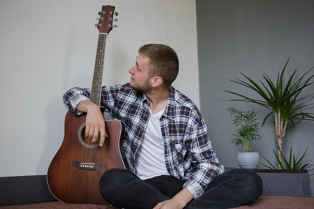 Homem de camisa xadrez, abraçando sua guitarra