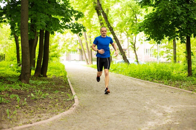 Homem de camiseta azul corre na floresta ou no parque. treino na floresta