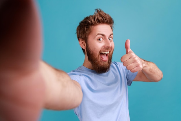 Homem de camiseta azul de bom humor mostrando o polegar para baixo como gesto tirando selfie POV