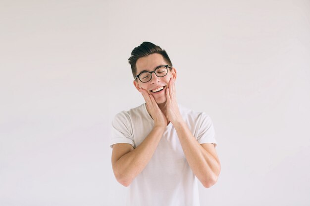 Homem de camiseta branca e óculos com grande sorriso isolado no branco. Um aluno muito gentil tem um bom humor