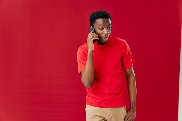 Homem de camiseta vermelha de aparência africana falando ao telefone emoções