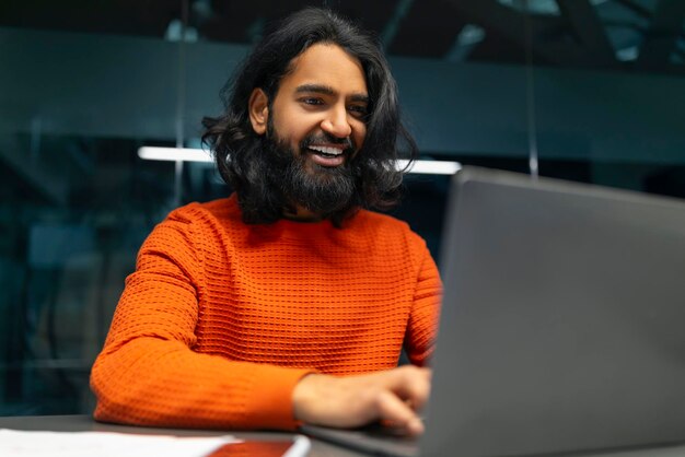 Foto homem de camisola laranja com laptop