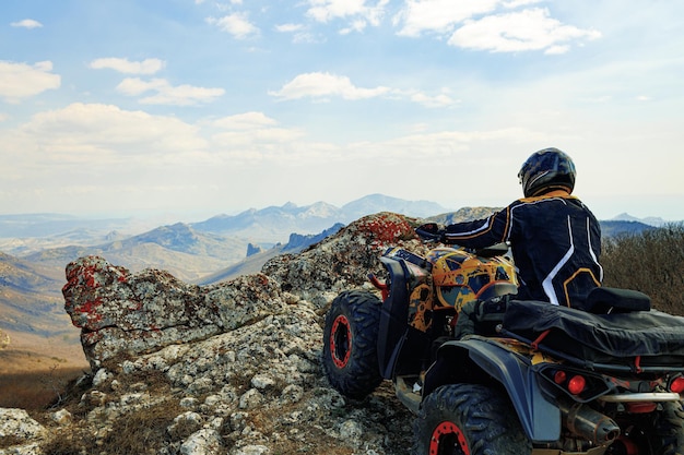 Foto homem de capacete sentado em um quadriciclo atv nas montanhas