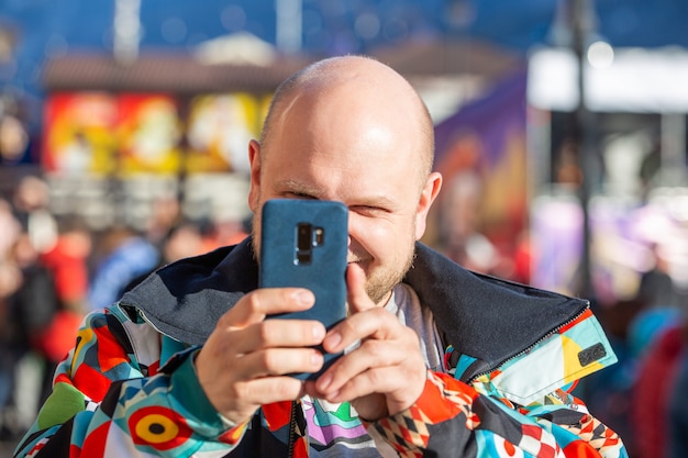 Homem de casaco tira fotos da paisagem no telefone