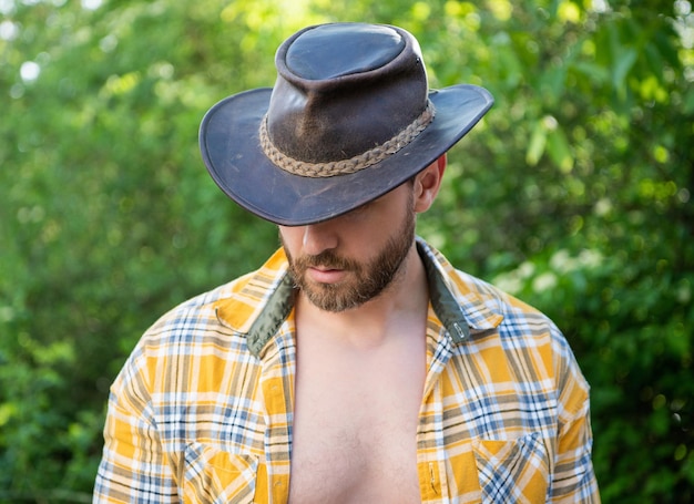 Homem de chapéu de cowboy olha para baixo cowboy sexy em camisa xadrez cowboy ocidental usando chapéu