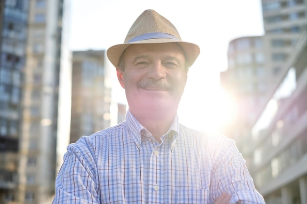 Homem de chapéu hispânico com bigode olhando para câmera sorrindo na cidade