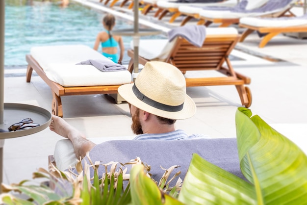 Homem de chapéu perto da piscina Férias de verão turismo de viagens e conceito de férias Conceito de viagem viajando negócios de hotel Água azul clara em uma piscina Banner