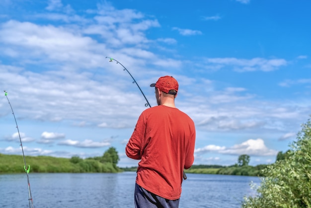 Homem de chapéu vermelho pescando em um lago