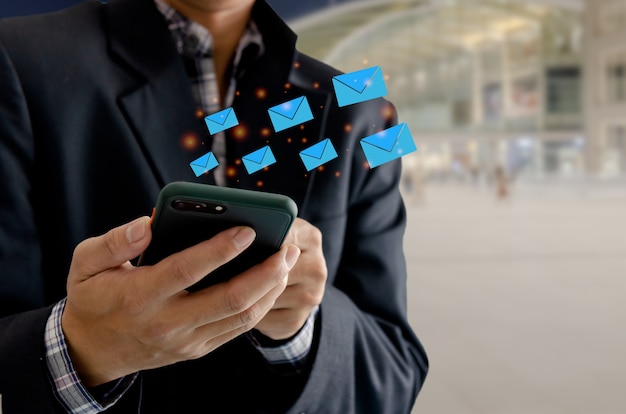 Homem de close-up segurando um telefone celular, uma mensagem de e-mail de ícone. Negócio de marketing, enviando informações para clientes ou hackeando transações online. Tecnologia de conceito de negócios.