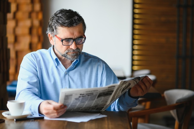 Homem de coffee-break tomando café e lendo jornal no café bar