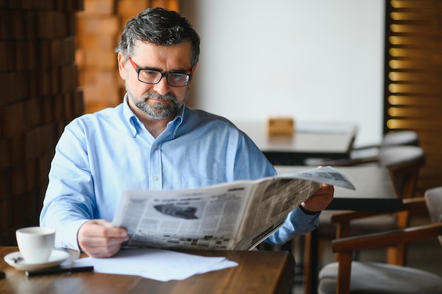 Homem de coffee-break tomando café e lendo jornal no café bar