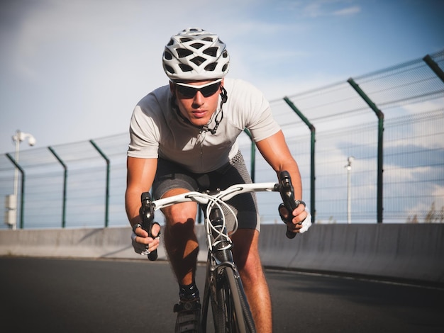 Homem de comprimento completo andando de bicicleta na estrada por corrimão