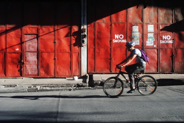 Foto homem de comprimento completo andando de bicicleta na rua contra o edifício