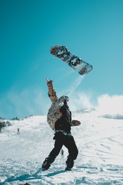 Foto homem de comprimento inteiro a brincar na neve.