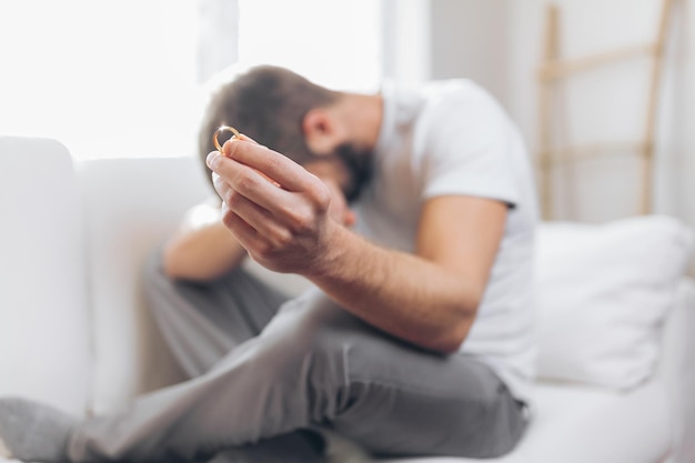 Homem de coração partido segurando um anel de casamento