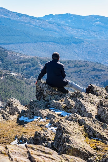 Homem de costas escalou algumas rochas enquanto contemplava a paisagem montanhosa da Sierra del Rincon Madrid