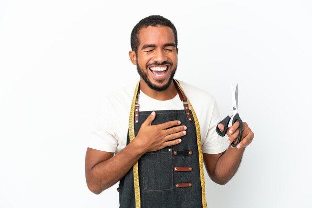 Homem de design equatoriano jovem segurando uma tesoura isolada no fundo branco sorrindo muito