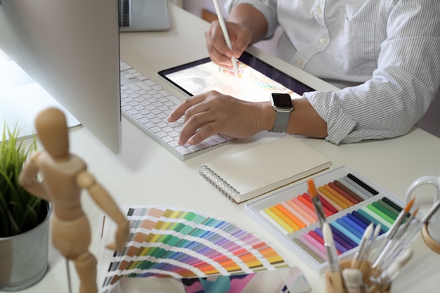 Homem de designer trabalhando com tablet no espaço de trabalho de estúdio