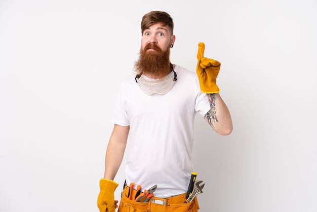 Homem de eletricista ruiva com barba longa sobre parede branca isolada, apontando com o dedo indicador uma ótima idéia