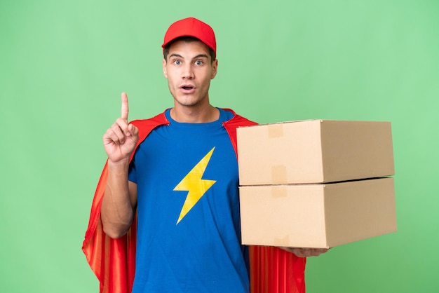 Homem de entrega do super-herói sobre fundo isolado, pensando uma ideia, apontando o dedo para cima