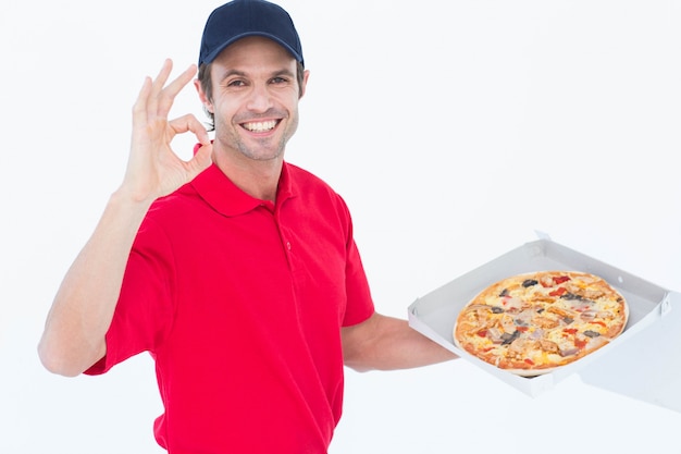 Homem de entrega gesticulando bem enquanto segura pizza fresca
