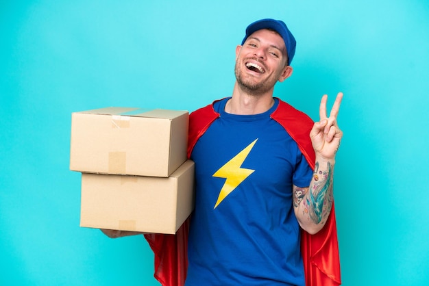 Homem de entrega super-herói sobre fundo isolado, sorrindo e mostrando sinal de vitória