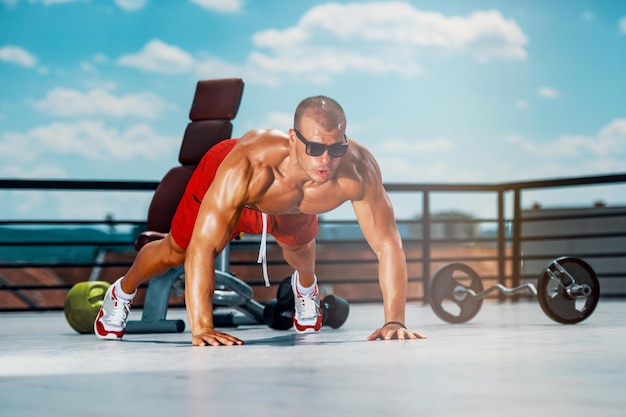Homem de esportes fazendo flexões no ginásio ao ar livre em um dia ensolarado