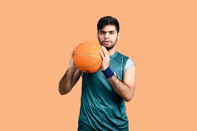 homem de esportes segurando basquete e olhando modelo paquistanês indiano frontal