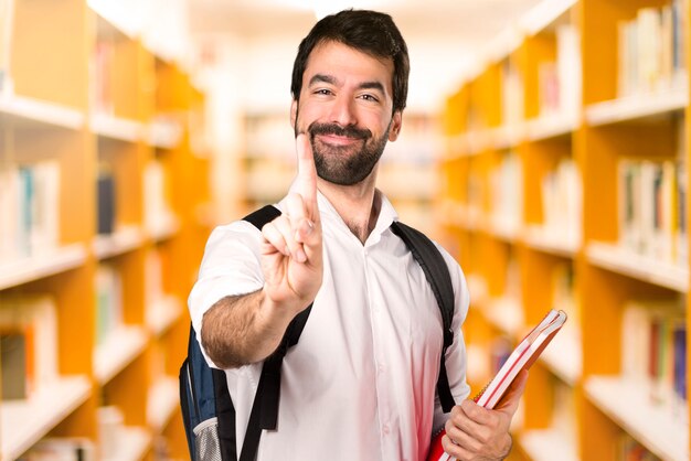 Homem de estudante contando um na biblioteca desfocada