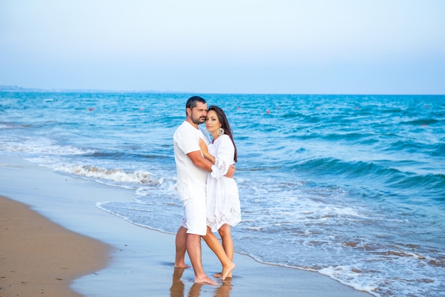 Homem de família feliz elegante e atraente e mulher caminhando na costa do mar. jovem esposa e marido apaixonado.