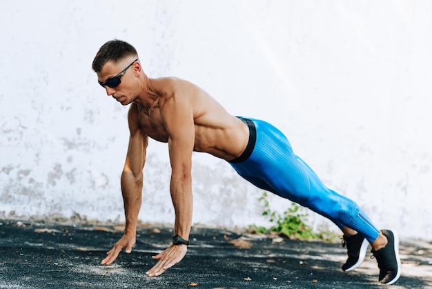 Homem de fitness forte fazendo exercício para peito ao ar livre contra parede de concreto Copie o espaço para publicidade Esportista fazendo exercícios de flexões do lado de fora